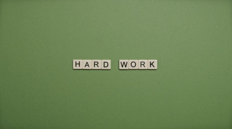 Tiles spelling 'hard work' on a green background symbolizing diligence and effort.
